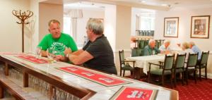 La Villette Hotel في سانت مارتن غيرنسي: رجلان يقفان على طاولة في مطعم