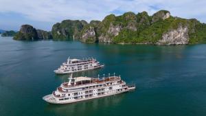zwei Kreuzfahrtschiffe im Wasser vor Kalksteinfelsen in der Unterkunft Paradise Elegance Cruise Halong in Hạ Long