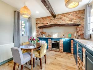 cocina con armarios azules, mesa y sillas en Owl Barn, en Benington