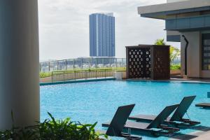 einen Pool mit Stühlen und ein Gebäude in der Unterkunft Seabreeze Seaview Super Cosy Stay Bali Residence in Malakka