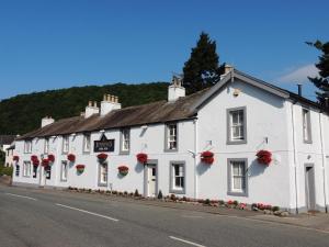 a white building with red flowers on it on a street at Sun Inn in Pooley Bridge