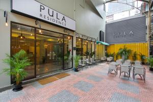 a patio with chairs and tables in a building at Pula Silom in Bangkok