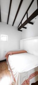uma cama branca num quarto com tectos em madeira em Villa Lucín em Santander