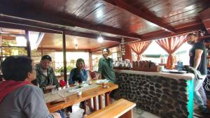 Pelangi Guest House في Kayu Aro: مجموعة من الناس يجلسون على طاولة في مطعم