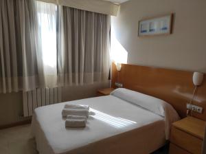 a hotel room with a bed with two towels on it at AT home Avenida del Ejercito in Guadalajara