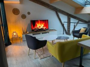 a living room with a tv and a table and chairs at Maison esprit loft in Courbesseaux
