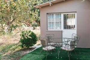 een glazen tafel en stoelen op een groen gazon bij The Mills House in Kallithea