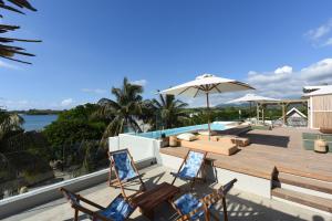una terraza con sillas, una sombrilla y una piscina en Veranda Tamarin Hotel & Spa en Tamarin