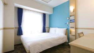 um pequeno quarto com uma cama e uma janela em Toyoko Inn Nishi Funabashi Baraki Inter em Ichikawa