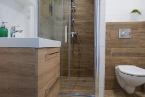 a bathroom with a shower with a toilet and a sink at CHILLIapartamenty - Navigator - MUSTANG in Kołobrzeg