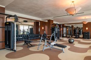 una sala de fitness con varias cintas de correr y pesas en The Ned Doha, en Doha