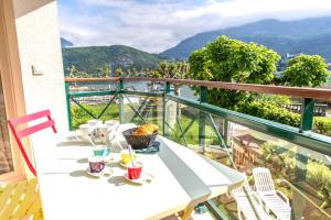 d'une table et de chaises blanches sur un balcon avec vue. dans l'établissement La Baie des Voiles, FEET IN THE CRYSTAL WATERS, 9 Apts from studio to Duplex, LLA Selections by Location lac Annecy, à Duingt