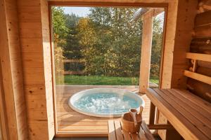 una bañera de hidromasaje en una terraza en una cabaña de madera en Jakob Chalets, en Perasdorf