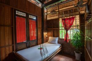 a bedroom with a bed in a room with windows at Tra Que Flower Homestay in Hoi An