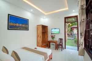 a bedroom with two beds and a tv and a window at Tra Que Flower Homestay in Hoi An
