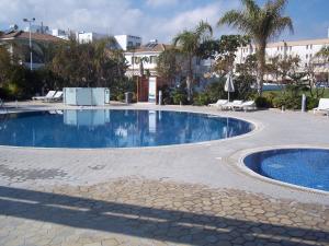 a large swimming pool in a resort with palm trees at Bowker Apartment in Protaras