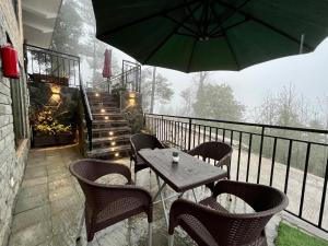 穆里的住宿－Ortus - Murree Hills，阳台配有桌椅和遮阳伞