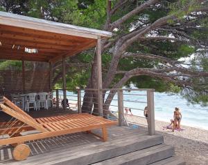a pavilion on the beach with people on the sand at Kamp Dole - Navores in Živogošće