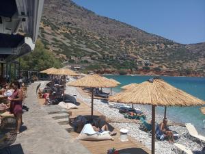a group of people laying on a beach with umbrellas at Nektarios Village House in Neápolis