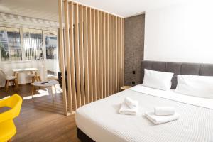 a bedroom with a white bed and a yellow chair at VH Executive Suites in Thessaloniki