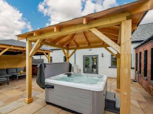 Westertonhill Holiday Lodges في بالوتش: حوض استحمام ساخن تحت ممر خشبي على الفناء