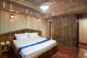 a large bed in a room with wooden walls at KMA SHWE PYI BAGO Resort in Bago