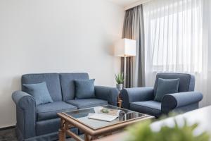 a living room with two blue chairs and a coffee table at Garner Hotel Rüsselsheim by IHG in Rüsselsheim