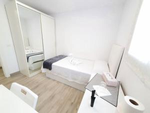 a white bedroom with a bed and a mirror at Habitaciónes bonitas y cómodas in Hospitalet de Llobregat