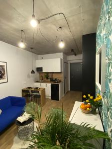 a living room with a blue couch and a kitchen at Apartamenty Silver Place in Szczecin