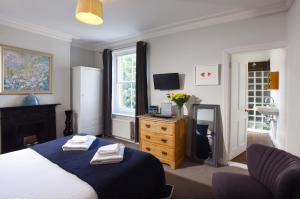 a bedroom with a bed and a dresser and a television at Old Fire Station Canterbury in Canterbury