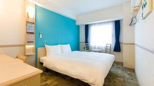 une chambre d'hôtel avec un lit et un mur bleu dans l'établissement Toyoko Inn Fuji Kawaguchiko Ohashi, à Fujikawaguchiko