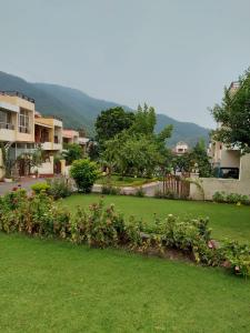 a green yard with some flowers and houses at Luxury Cottage by iTvara in Rishīkesh