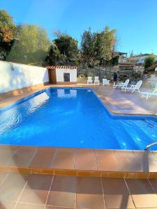 une grande piscine bleue avec des chaises et des tables dans l'établissement Villa Girasol, à Vidreres