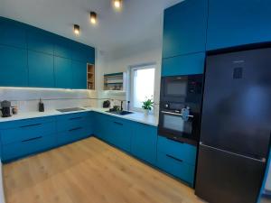 una cocina azul con encimeras blancas y armarios azules en Chabrowa Apartamenty 1, en Milicz