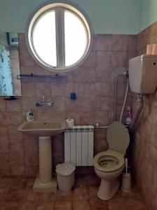 a bathroom with a toilet and a sink and a window at къща за гости Хайк in Beli Osŭm