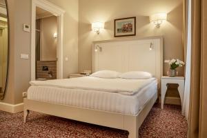 ein Schlafzimmer mit einem großen weißen Bett und einem Spiegel in der Unterkunft Ratonda Centrum Hotels in Vilnius