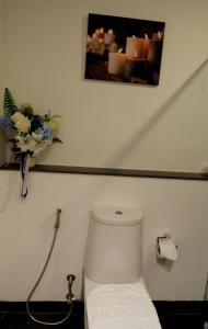 um WC branco numa casa de banho com um vaso de flores em The Midst by The M - Nakhon Nayok TMD4 em Ban Som Phung Haeng (1)