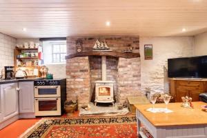 a kitchen with a stone fireplace with a stove at The Byre (Unusual and Different). in Dromore