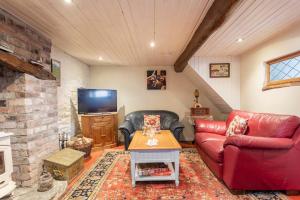 a living room with a red couch and a tv at The Byre (Unusual and Different). in Dromore