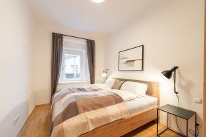 a white bedroom with a bed and a table at Premium Apartments im Stadtzentrum in Graz