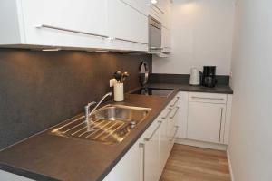 a kitchen with a stainless steel sink and white cabinets at Ferienwohnung zur Seeseite _ 200 m in Damp