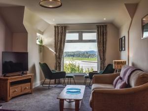 a living room with a couch and chairs and a television at Teds Place in Arnside