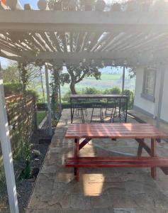 een houten picknicktafel onder een witte pergola bij Koru Farm Retreat in Muhoroni