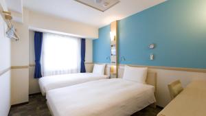 a hotel room with two beds and a window at Toyoko Inn Meitetsu Chiryu Ekimae in Chiryu