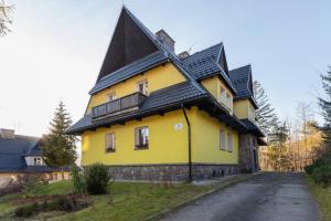 uma casa amarela com um telhado preto numa estrada em Apartament Salamandra Giewont View by Renters Prestige em Zakopane