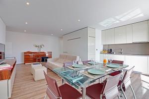 Una cocina y una sala de estar con una mesa de cristal y sillas. en Sky Beach Apartment, en Quarteira