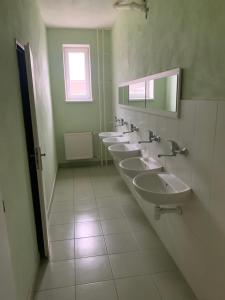 Baño con 4 lavabos y una fila de espejos en Hostel SOS Moldava, en Moldava nad Bodvou