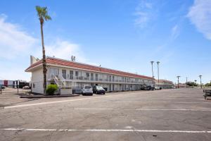 ein großes Gebäude mit einer Palme und einem Parkplatz in der Unterkunft Super 8 by Wyndham Phoenix West in Phoenix