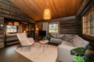 una sala de estar con sofá y sillas en una cabaña de madera en Villa Huippu, en Syöte