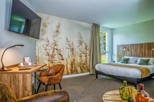 a hotel room with a bed and a desk and chairs at Les Jardins de l'Anjou in La Pommeraye